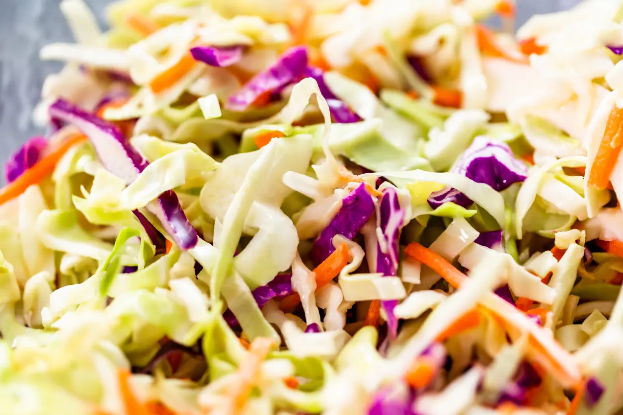New Project(4) Close-up of a mixed coleslaw salad, featuring shredded green and purple cabbage with carrots.